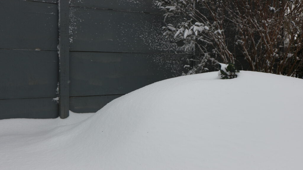 Schneehügel vor grauer Wand